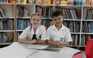 A photo showing two students from St Jerome's Catholic Primary School Punchbowl smiling and working in the library, on their way to 2025 NAPLAN success